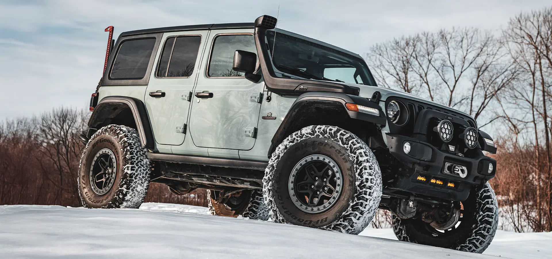 White Jeep Wrangler with large off-road tires on a snowy landscape | Satin Black Finish with Onyx Protection Ring (+25mm offset)