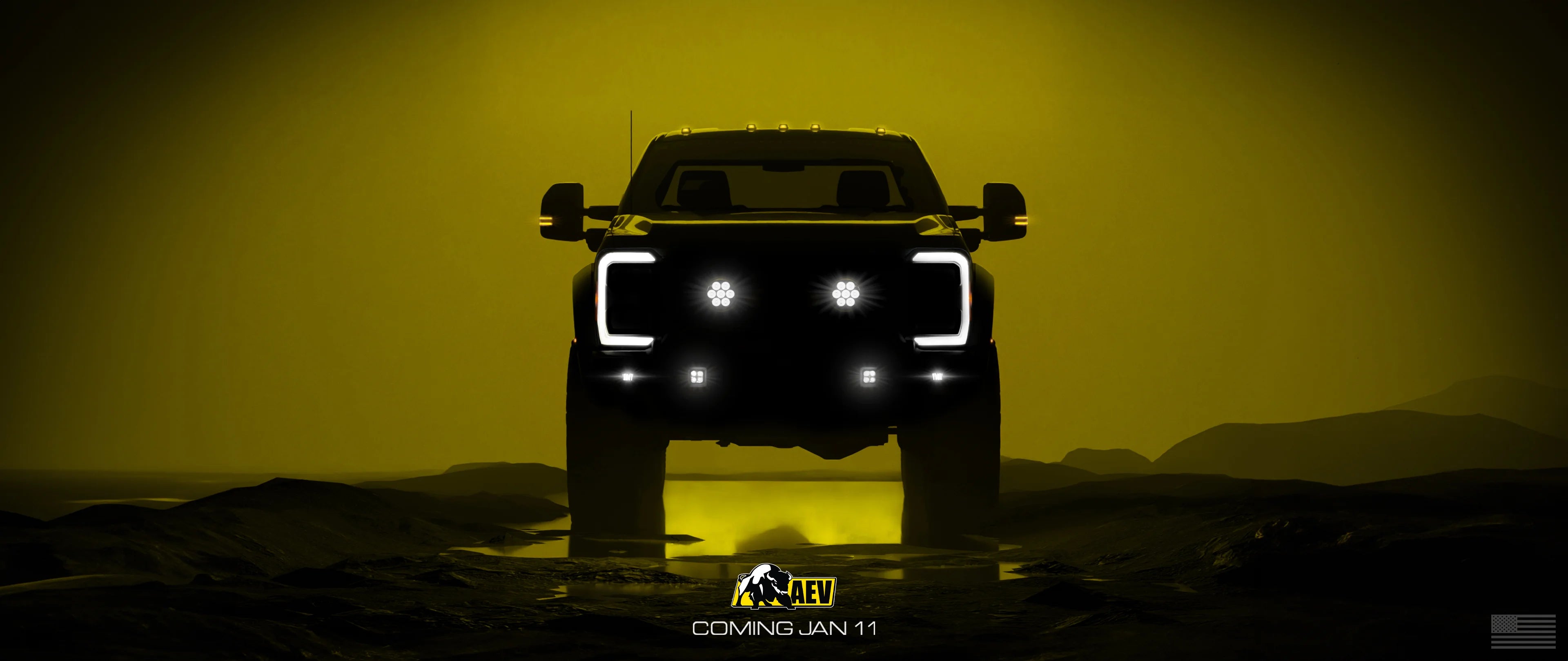 Silhouette of a truck with glowing headlights against a yellow background