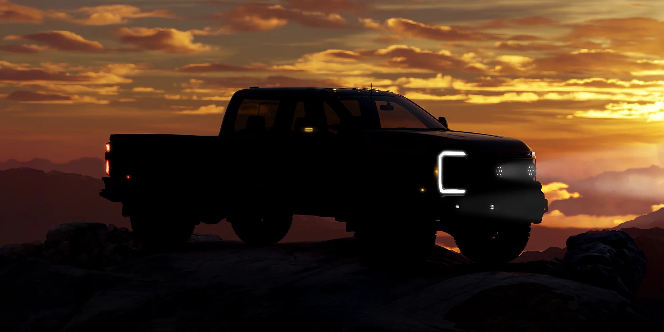 Silhouette of a pickup truck on a rocky landscape with a sunset sky